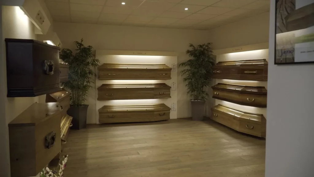 Exposition de cercueils en bois sur étagères lumineuses dans un showroom funéraire