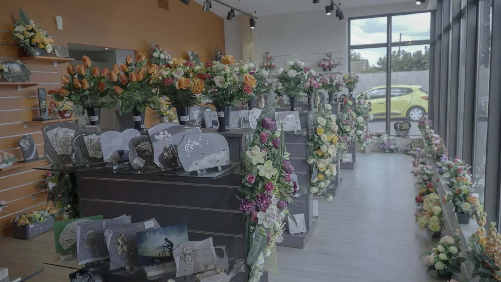 Présentation de plaques funéraires personnalisées et de fleurs de deuil en magasin