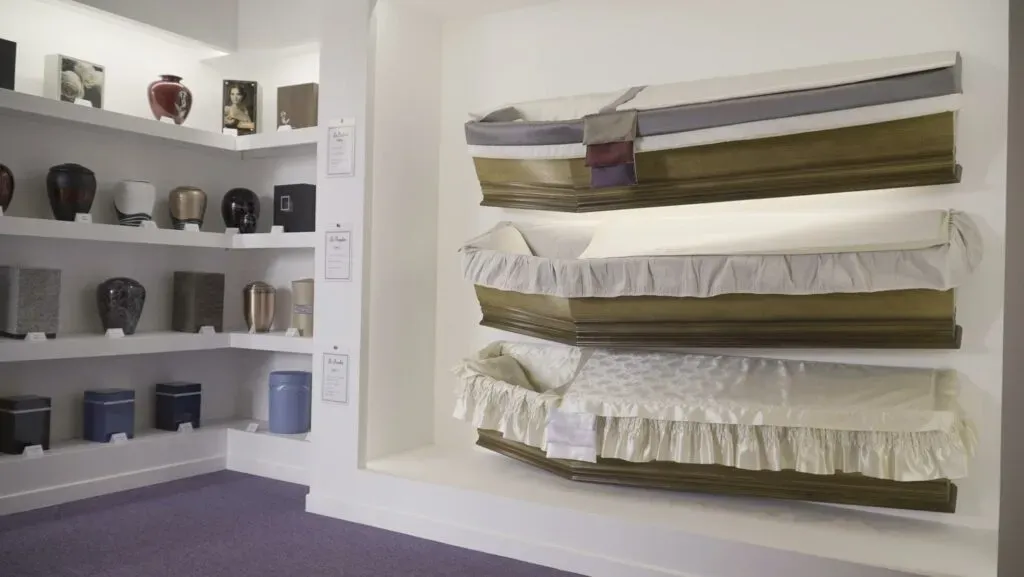 Exposition de cercueils en bois et étagères d'urnes cinéraires en showroom