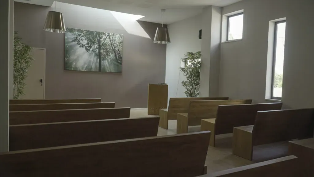 Salle d'hommage et de cérémonie avec bancs en bois et lumière naturelle